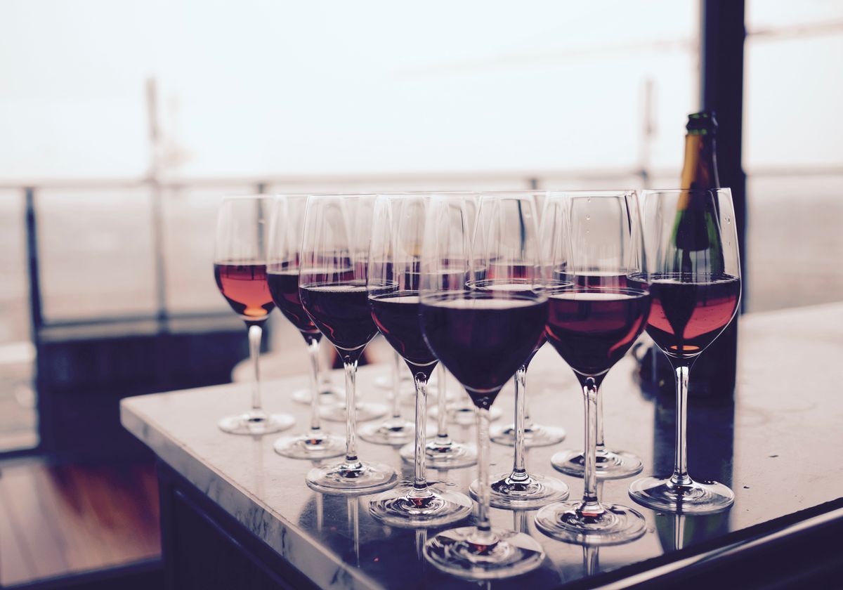 Glasses of red wine lined up on a bar counter