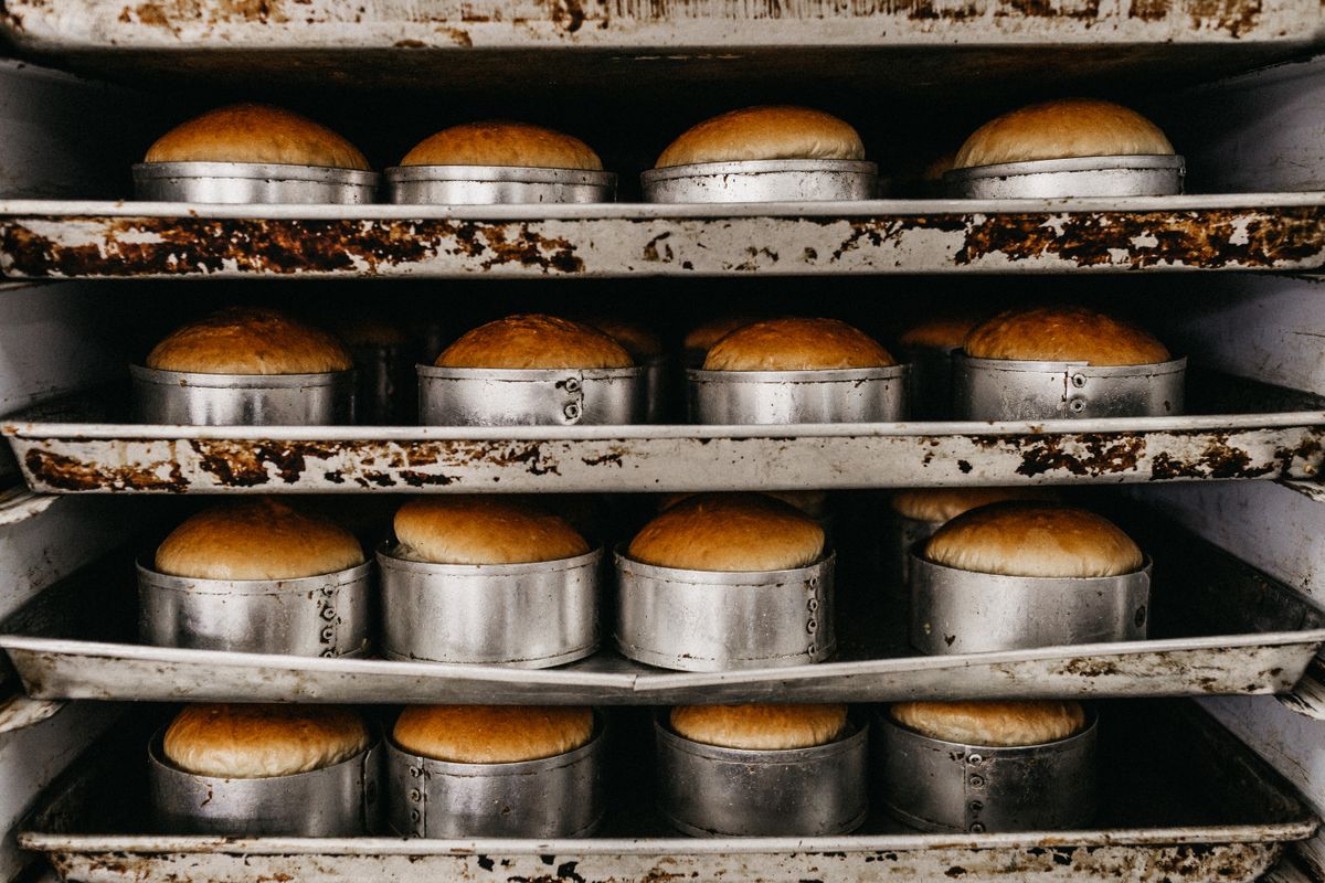 Rows of golden bread rolls in metal baking trays
