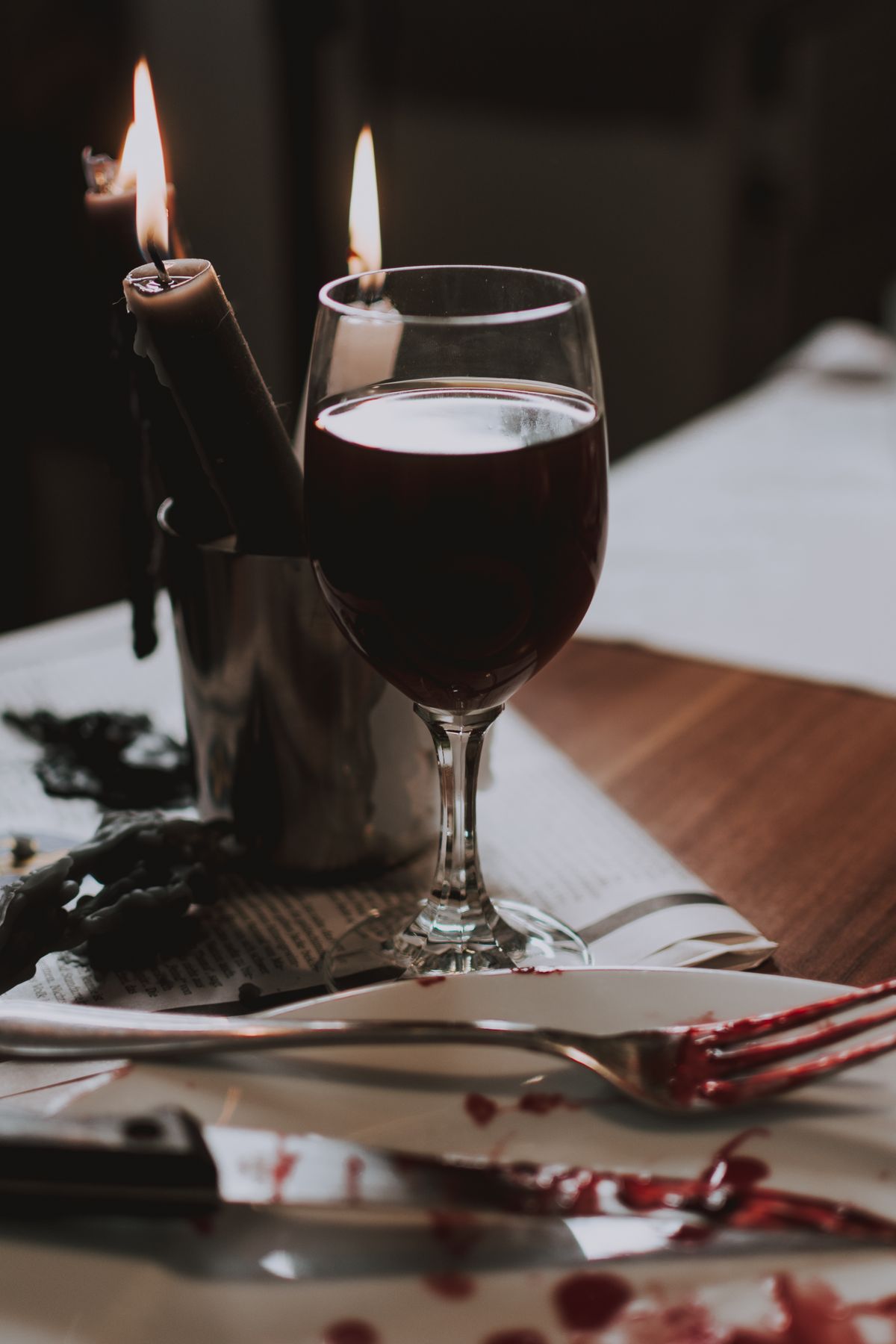A glass of red wine on a table beside candlelight